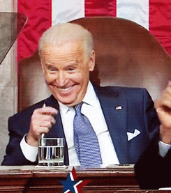 President Joe Biden sitting in a chair pointing and laughing 
